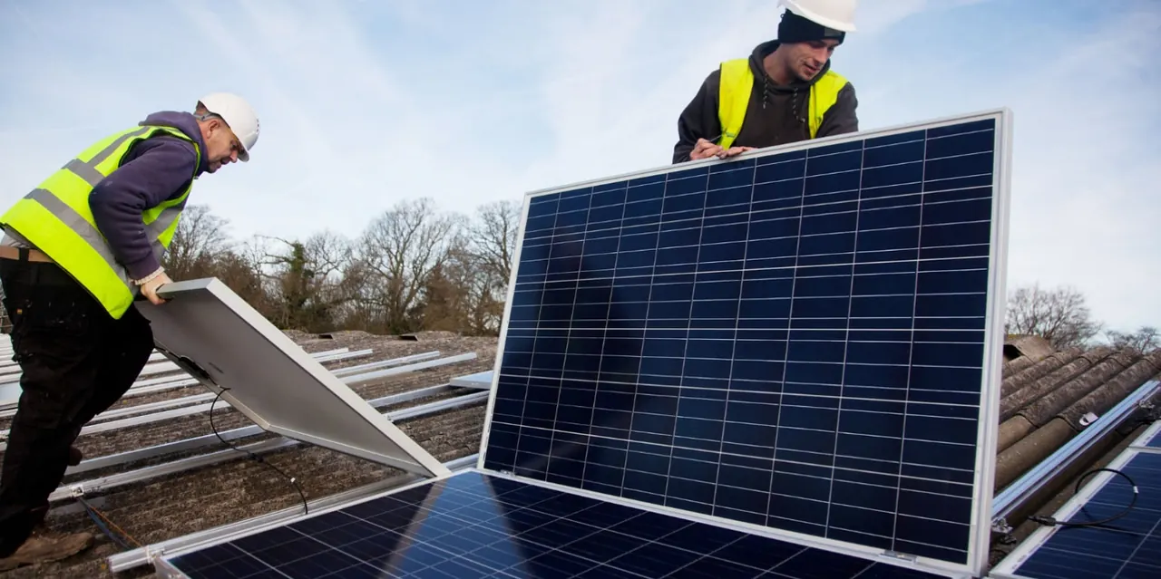 Dos profesionales instalan paneles solares sobre una cubierta